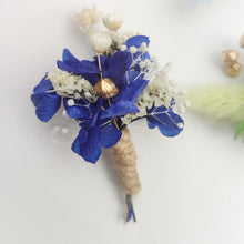 Charger l&#39;image dans la galerie, Boutonnière florale bleu foncé avec des fleurs de gypsophile et des détails dorés.
