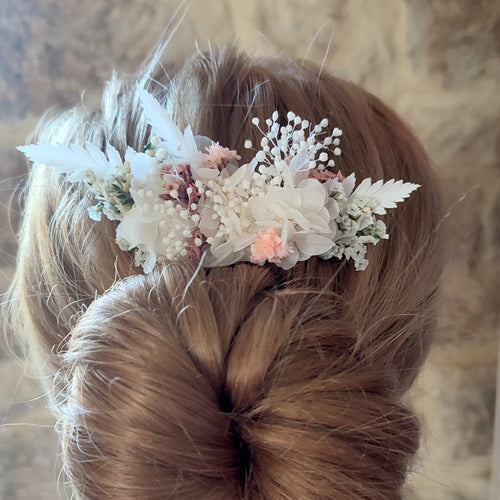 Peigne floral Clara avec des fleurs éternelles blanches et roses, inséré dans une coiffure élégante.