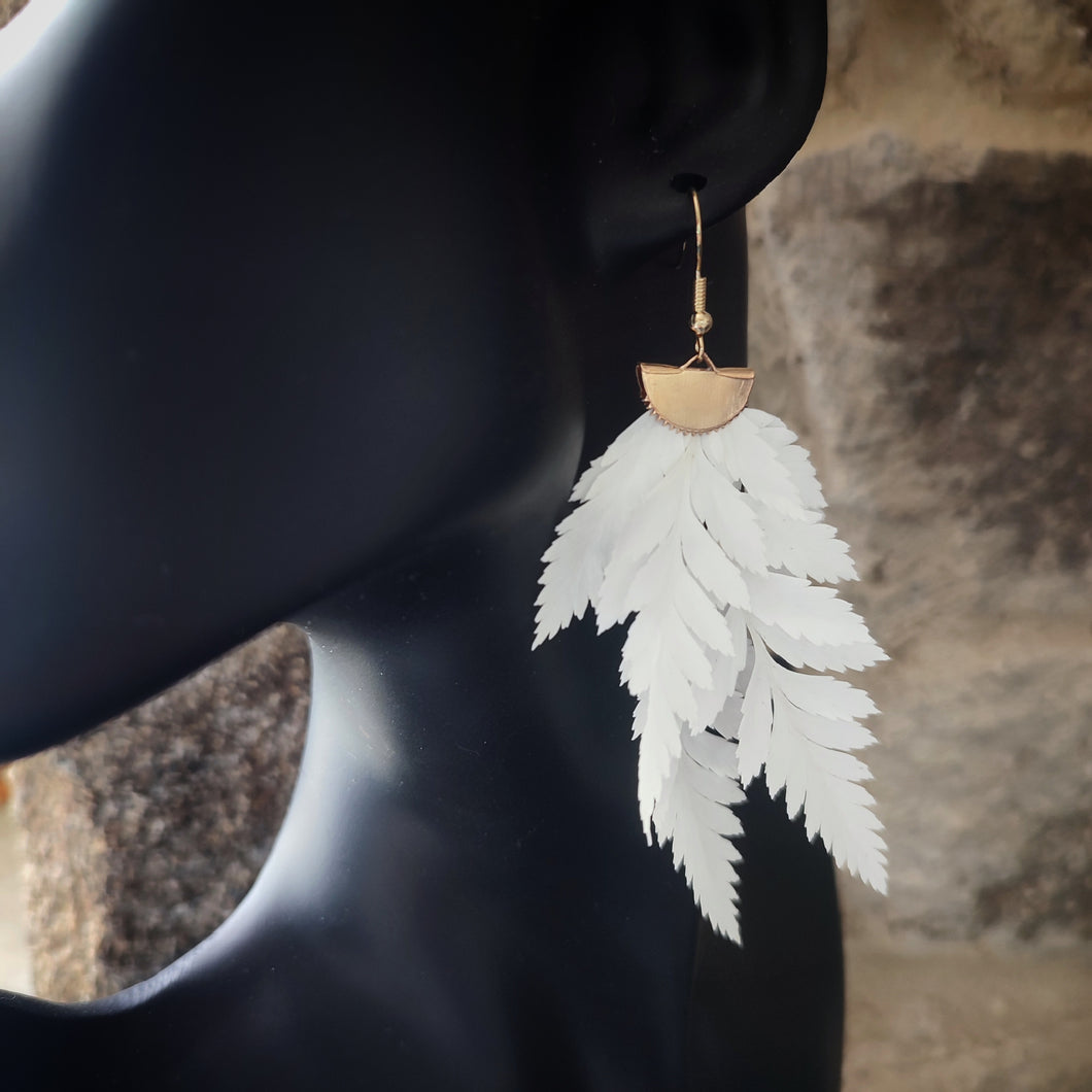 Vue rapprochée d'une boucle d'oreille en fougère stabilisées et séchées, mettant en valeur les détails des feuilles naturelles et le crochet en métal doré.